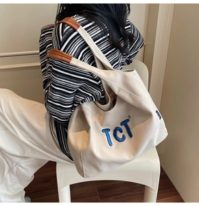 Détail du sac cabas en toile beige avec broderie TCT bleue et touches de cuir