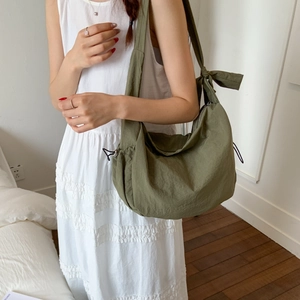 Detailed close-up of army green crossbody bag with decorative bow and side drawstring