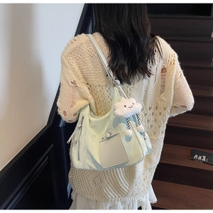 Detail view of light green tote bag with crinkle texture and white cloud plush charm