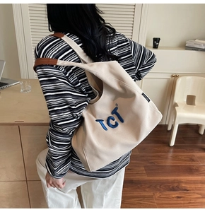 Détail du sac cabas en toile beige avec broderie TCT bleue et accents en cuir marron