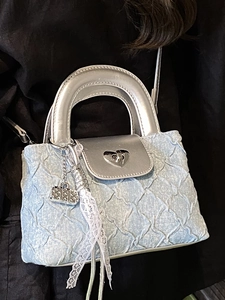 Light blue denim handbag with quilted texture, heart lock, and silver chain strap