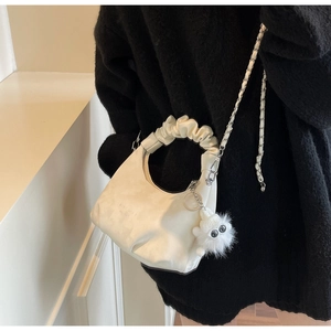 Detail of cream white pleated hobo bag with cloud handle and metal chain on model
