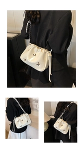 Vue détaillée du sac seau plissé crème avec fermoir papillon argenté et bandoulière chaîne