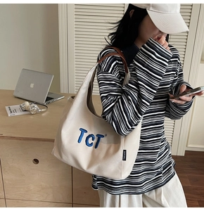 Détail du sac fourre-tout en toile beige avec broderie TCT bleue et étiquette latérale