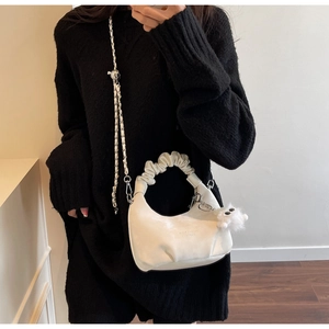 Detail of white cloud bag with pleated handle, silver chain and soft plush pompom charm