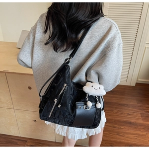Detail of black pleated shoulder bag with multi-zippers and cute cloud plush charm