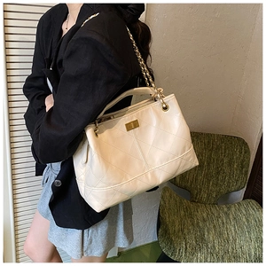 Detail of cream quilted handbag with gold chain strap and metallic turn-lock closure