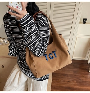 Detailed close-up of brown canvas tote bag with TCT embroidery and leather straps