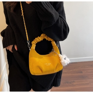 Detail of a bright yellow ruched cloud bag with a plush charm and silver chain strap