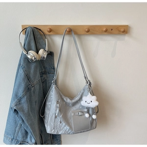 Detail of silver pleated shoulder bag with adjustable straps and cloud plush charm