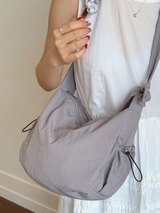 Minimalist grey dumpling shoulder bag with adjustable side drawstrings and nylon texture