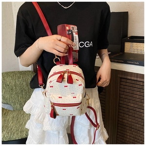 Gros plan du mini sac à dos blanc avec motifs nœuds rouges et bretelles en cuir