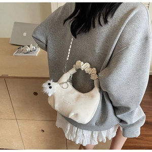 Detail of cream cloud bag with ruched handle, plush charm, and silver chain strap