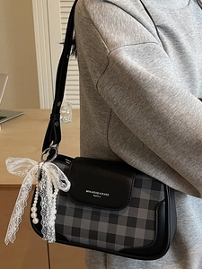 Schultertasche mit Punkten, Spitzenbogen und Perlenkette, getragen von einem Modell