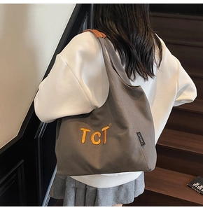 Détail du cabas en toile gris foncé avec broderie TCT orange et poignées en cuir chic