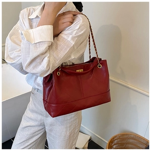 Detail shot of a dark red quilted tote bag with golden metal chain straps and clasp