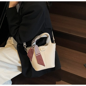 Detail view of cream white leather bucket bag with houndstooth silk scarf on handle