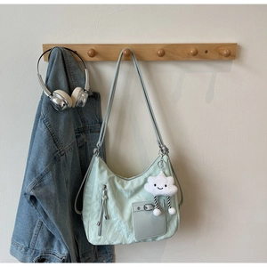 Detail of mint green tote bag with pleated texture and white plush cloud charm