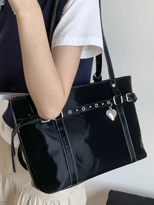Chic black patent leather bucket bag with silver heart pendant and stylish metal eyelets