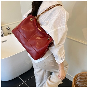 Detail of red quilted leather tote bag with gold chain strap and diamond stitching