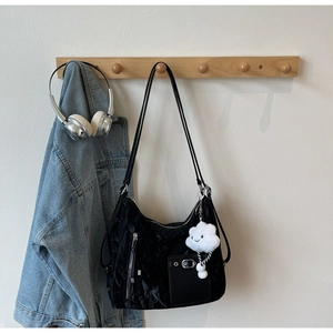 Close-up of black pleated tote bag with silver zipper detail and white cloud charm