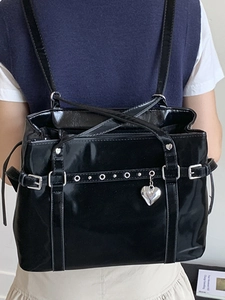 Chic black glossy bucket bag with silver eyelets and heart pendant for stylish women