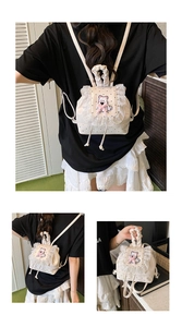Detail of a creamy white mini backpack with black polka dots, lace trim, and puppy embroidery