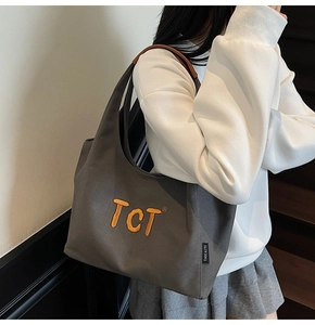 Détail du sac cabas en toile grise avec broderie TCT orange et poignées en cuir marron