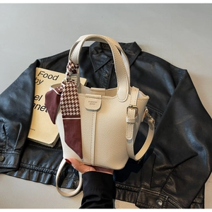 Detail of cream white pebbled leather bucket bag with houndstooth silk scarf on handle