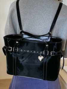 Fashionable black glossy bucket backpack with silver metal eyelets and a heart pendant