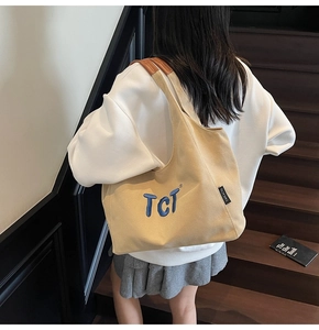 Détail du sac cabas en toile beige avec broderie bleue et poignées en cuir marron élégant