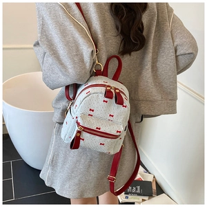 Vue arrière détaillée d'un mini sac à dos blanc avec des motifs de nœuds rouges