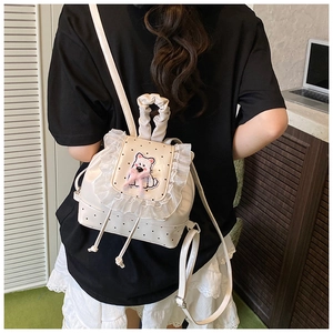 Detail of cream mini backpack with lace trim and polka dots on a model's back