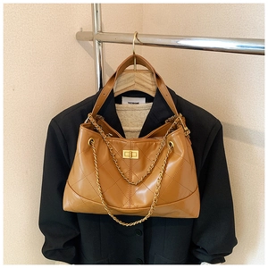 Detail of caramel quilted crossbody tote bag with gold chain strap and twist lock