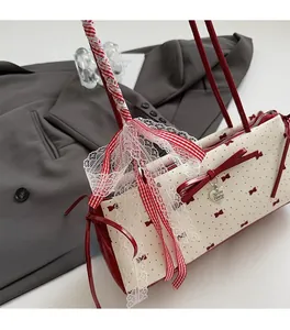 Detail of a chic bow-patterned handbag featuring a heart metal pendant and lace ribbons