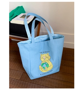 Detail of light blue canvas tote bag with cartoon cat print and blue checkered lining