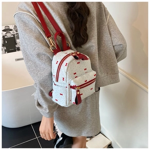 Mini sac à dos avec imprimés nœuds rouges porté par un mannequin dans une salle de bain
