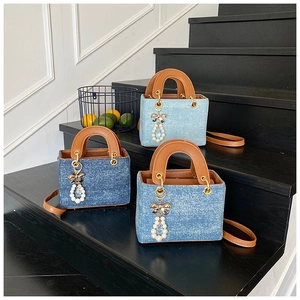 Detailed close-up of denim square tote bags in three blue shades with pearl bow charms