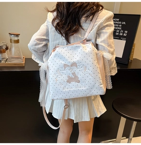 Detail of embroidered rabbit and lace trim on a white polka dot backpack with pink straps