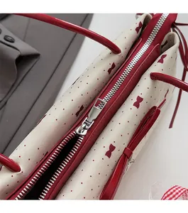 Detail view of the smooth metallic zipper closure on the beige polka dot bow bag