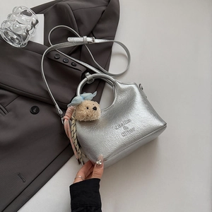Detail of silver crescent bucket bag with adjustable strap and cute teddy bear charm