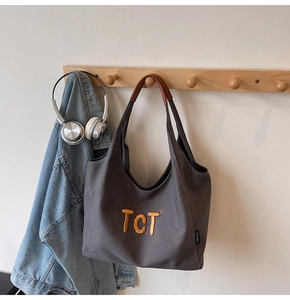Détail du cabas en toile gris foncé avec broderie TCT orange et poignées en cuir