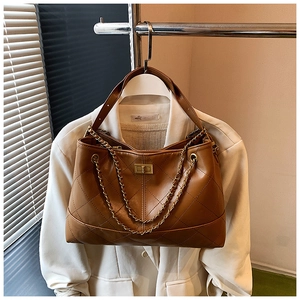 Close-up of retro brown quilted tote bag with golden metal chain and twist-lock detail