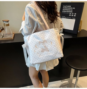 Detail of white quilted tote with black polka dots, lace edges, and rabbit embroidery