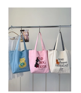Detailed close-up of three canvas tote bags in blue, pink, and white with checkerboard handles