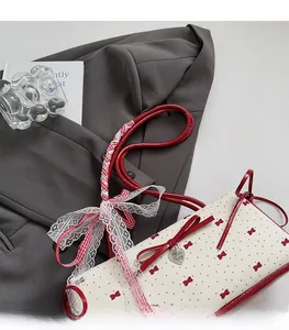 Detail of red bow charm and lace ribbon on a white polka dot baguette bag