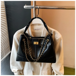 Close-up of black quilted leather tote featuring gold chain straps and turn-lock buckle