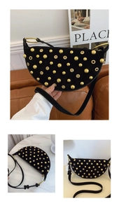Close-up of black suede crescent bag featuring dense gold studs and metallic eyelets