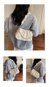 Detail der cremeweißen Cloud-Bag mit feiner Lychee-Narbung und dekorativem Perlenriemen