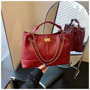 Detail of red quilted tote bag featuring golden turn-lock clasp and chain strap